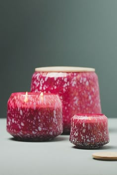 three red candles sitting next to each other on top of a white table with wooden coasters