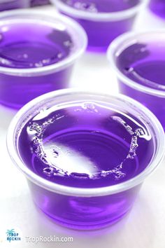 purple cups filled with liquid sitting on top of a table