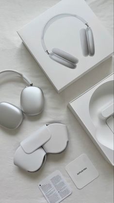 two white headphones are sitting on a table next to a box and other accessories