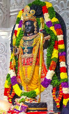 a statue of the hindu god maha in front of flowers and garlands on display