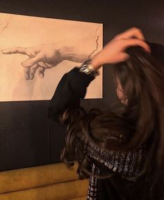 a woman with long hair standing in front of a painting