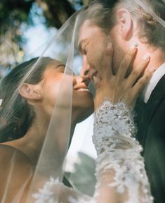 a bride and groom kissing under a veil