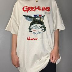 a woman standing in front of a wall wearing a t - shirt with gremlin's on it