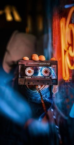 a person holding an old fashioned cassette in front of a graffiti wall