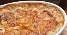 a close up of a casserole in a white dish on a wooden table