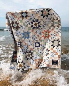 an old quilt on the beach with waves coming in to shore and blue sky above