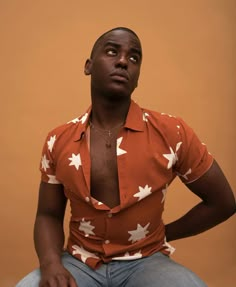 a man sitting on top of a chair wearing an orange shirt with white maple leaves