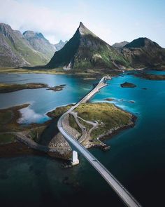 an aerial view of a bridge crossing over water with mountains in the backgroud