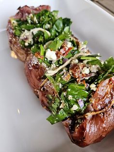 a white plate topped with meat covered in greens