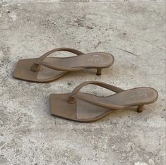 two pairs of brown sandals sitting on top of a cement floor next to each other