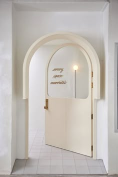 an arched doorway leading into a bathroom with white tile flooring and walls that have gold lettering on it