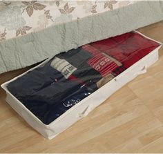 an open suitcase on the floor next to a bed with red and blue blankets in it