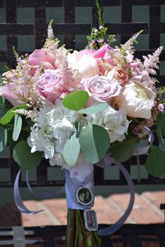 a bouquet of flowers sitting on top of a wooden table next to a bench with ribbon