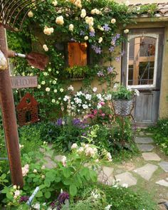 a garden with flowers and plants in front of a house that has a welcome sign on it