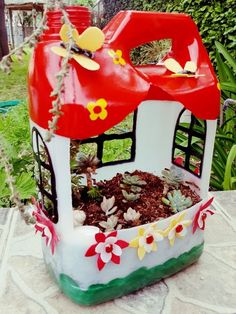 a house shaped planter with flowers and plants in it