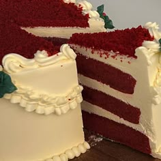 a red velvet cake with white frosting and green leaves on the top is cut in half