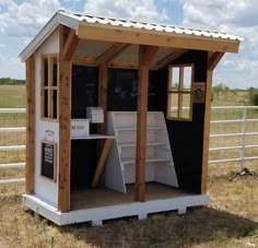 a small white shed sitting on top of a dry grass field