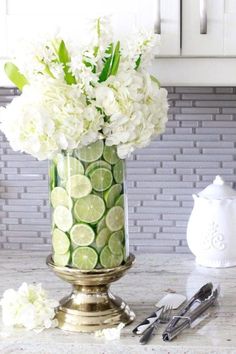 a vase filled with white flowers and cucumber slices on top of a counter