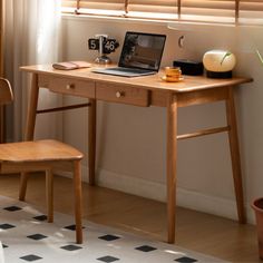 a laptop computer sitting on top of a wooden desk next to a chair and window