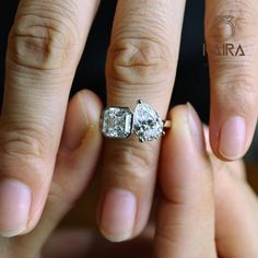 a woman's hand with two engagement rings on it