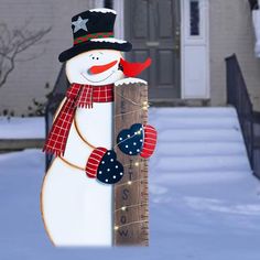 a snowman holding a ruler in front of a house with christmas decorations on it