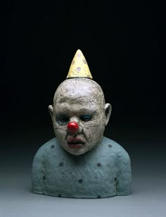 a creepy looking statue with a clown's head wearing a party hat on top of it