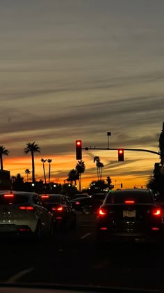 cars are stopped at an intersection as the sun is setting in the sky behind them