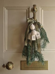 a door hanger decorated with pine branches and bells