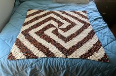 a crocheted blanket sitting on top of a blue bed in a room with white walls