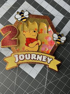 a winnie the pooh birthday cake topper on a checkered tablecloth background