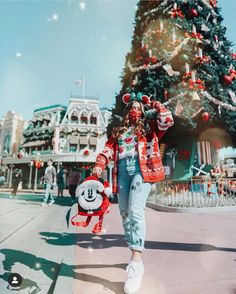 a woman walking down the street in front of a christmas tree