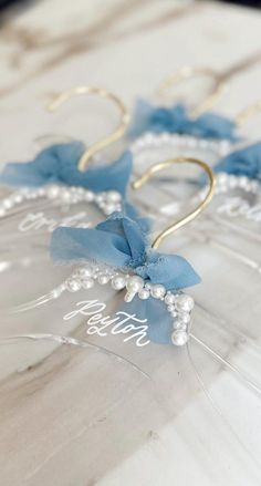 two blue bows are tied to the side of some clear acrylic earrings with pearls