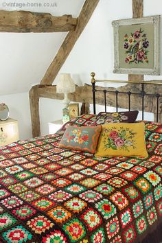 a bed with a quilt and pillows on it in a room that has exposed wood beams