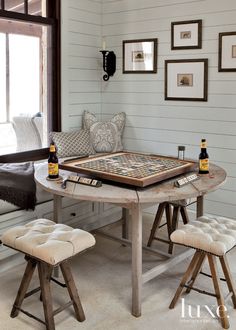 a table with two stools in front of it and some pictures on the wall