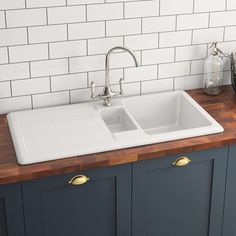 a white kitchen sink sitting on top of a wooden counter