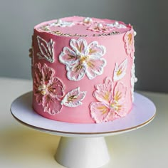 a pink cake decorated with flowers and pearls