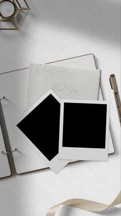 an open notebook with two black and white photos on it, next to a pen