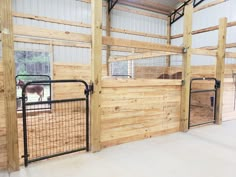 the inside of a barn with wooden walls and metal gated in area for horses