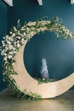 a cake sitting on top of a moon with greenery around it