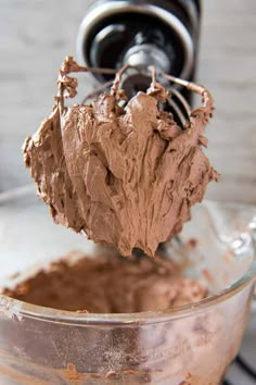 a mixer filled with chocolate frosting being stirred