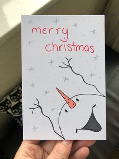 someone is holding up a christmas card with a snowman's face on it