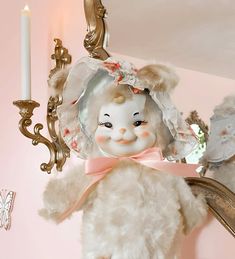 a white teddy bear sitting on top of a table next to a mirror and candle