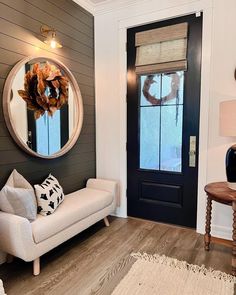 a white couch sitting in front of a door next to a table with a mirror on it