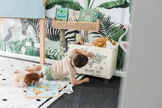 a little boy is playing with his toys in the room that's decorated with tropical wallpaper