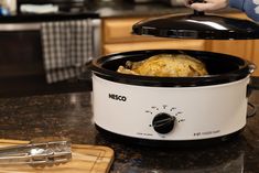 a crock pot sitting on top of a counter next to a cutting board