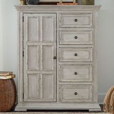 an old white dresser with drawers and baskets on top