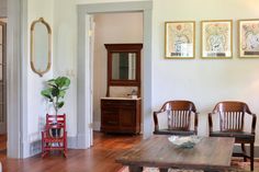 a living room filled with furniture next to a wooden table and mirror on the wall