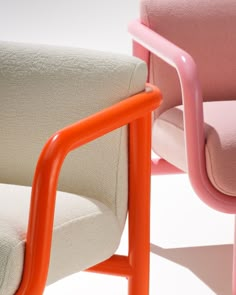 an orange and pink chair sitting next to each other on a white surface with no one in it