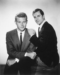 two men sitting next to each other in suits