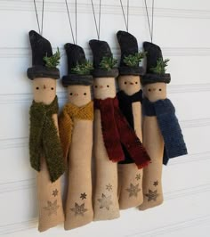 four wooden peg dolls with hats and scarves hanging on a wall